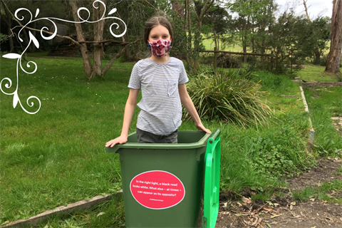 A child wearing a face mask stands in a rubbish bin with a haiku sticker on it