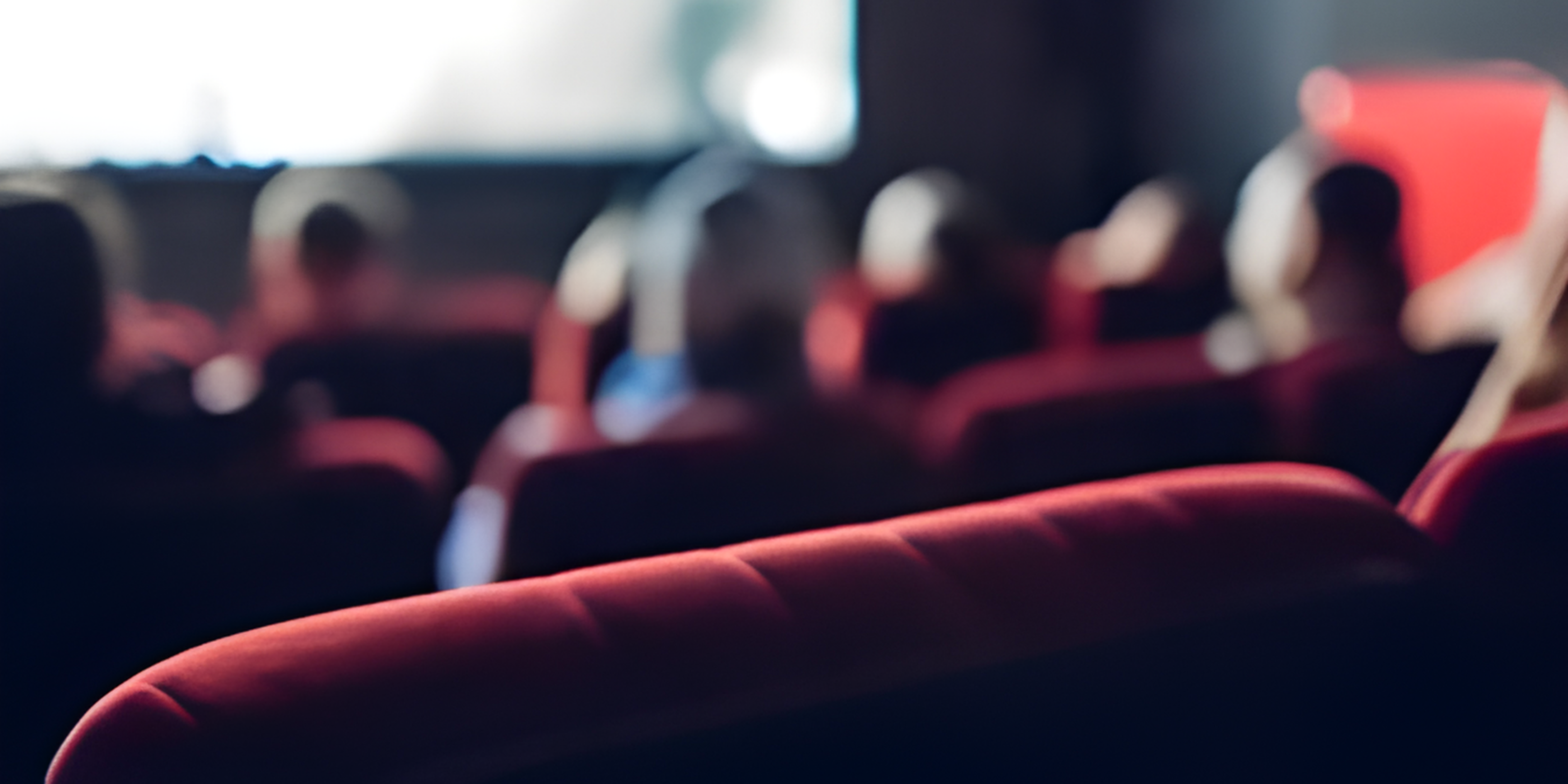 Back of cinema chair and heads, facing cinema screen