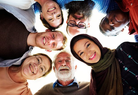 Diverse group of people standing in a circle looking at the camera