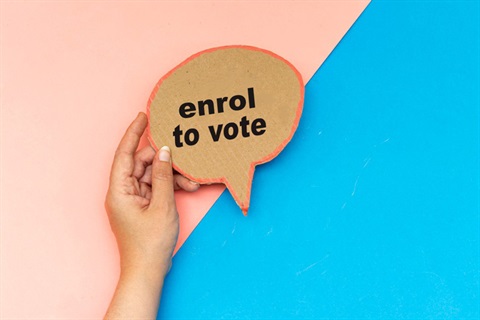 person holding a enrol to vote sign