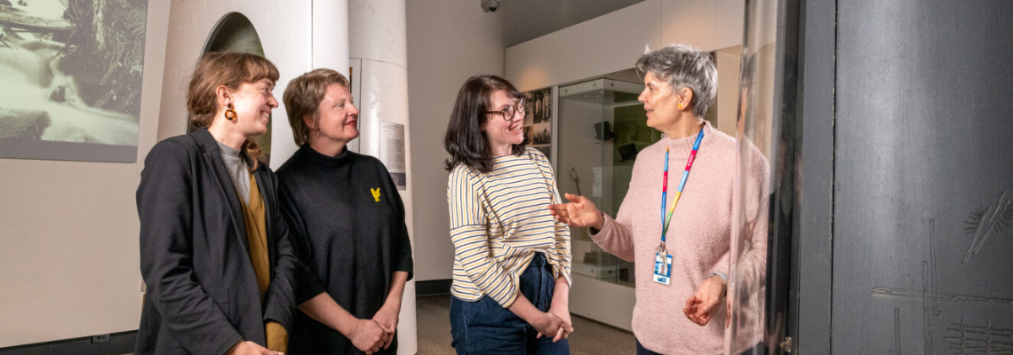 A group listening to a museum curator talking about the museum collection