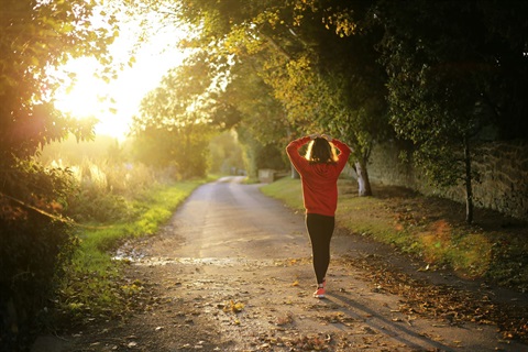 women going for a walk at sunrise she is wearing leggings and a red jumper