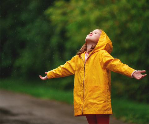 A child stands in the rain in a yellow raincoat