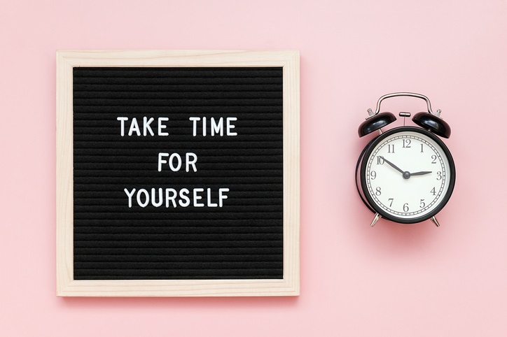 a slate board says 'take time for yourself' beside an alarm clock