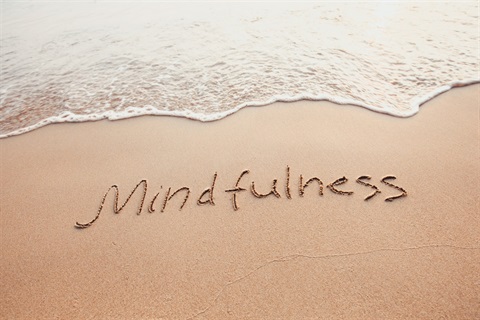 The word 'mindfulness' written in the sand