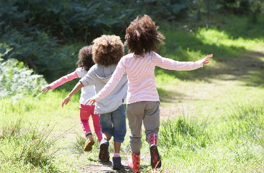 Three young children walking down a path in a park