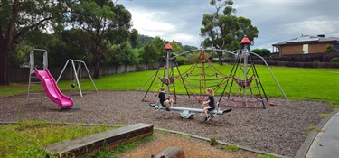 Play equipment featuring slide, see-saw, swings and climbing elements