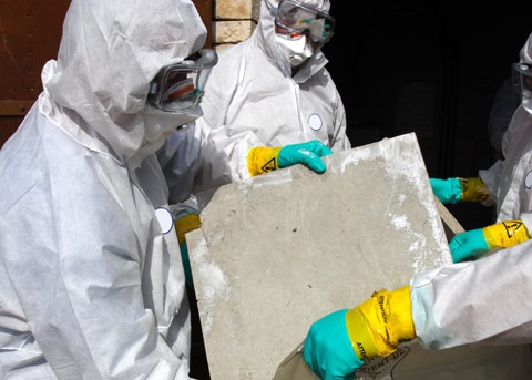 Professionals wearing protective clothing removing asbestos